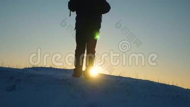 旅行者克服困难走向胜利. 旅行者在阳光的照耀下在一座雪山上站起来。 游客